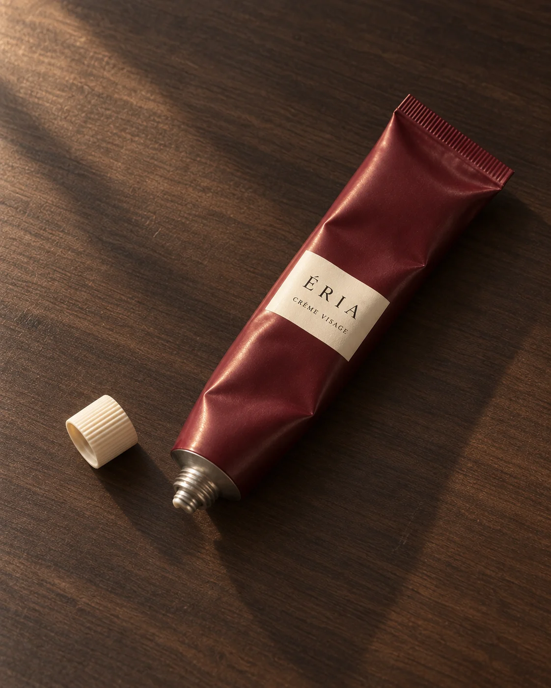 Tube de crème visage bordeaux posé sur du bois fumé