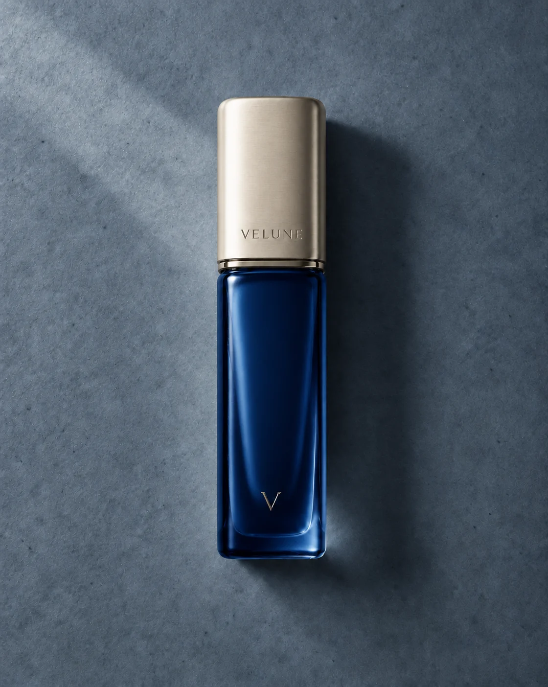 Flacon de parfum bleu profond sur fond minéral bleu